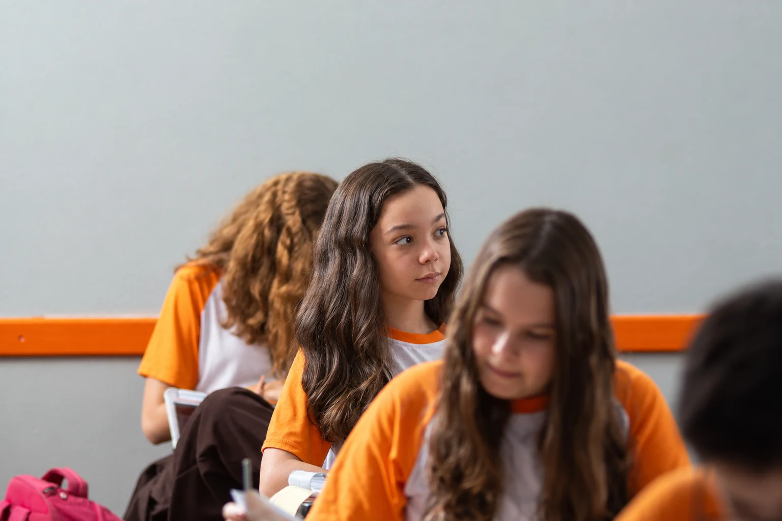 Adolescente olha para quem fala à frente da sala