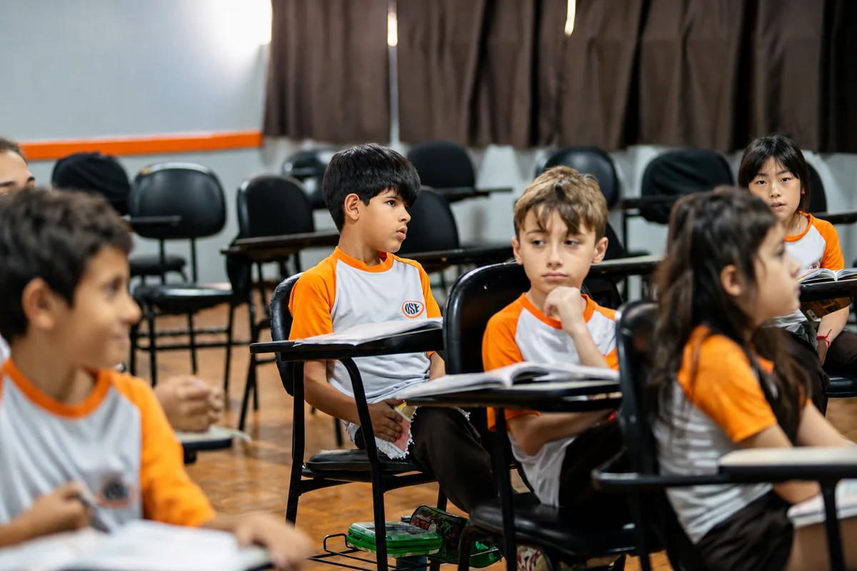 Turma do Fundamental I com os livros abertos nas carteiras do auditório