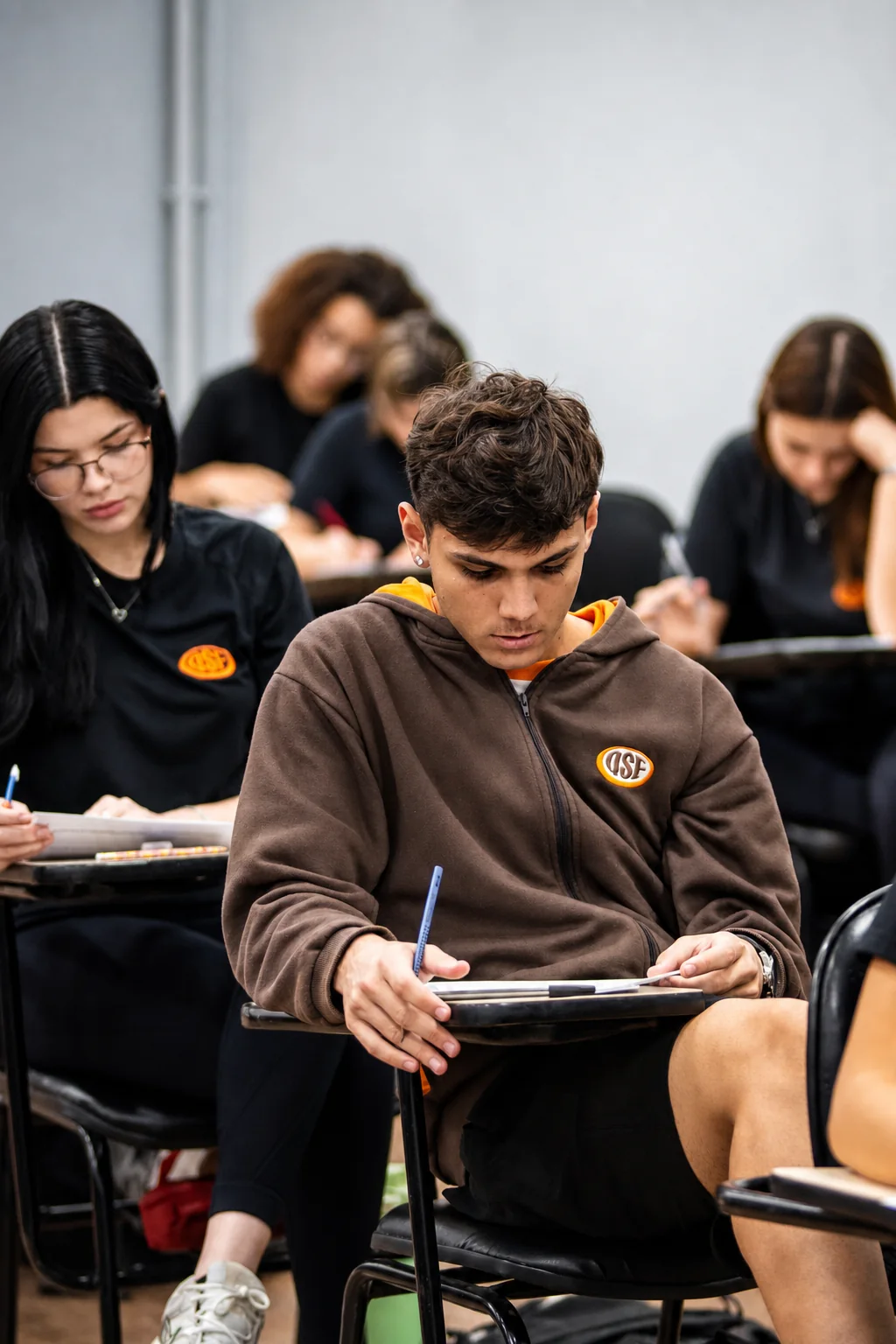Aluno do Ensino Médio de moletom do uniforme escreve na carteira