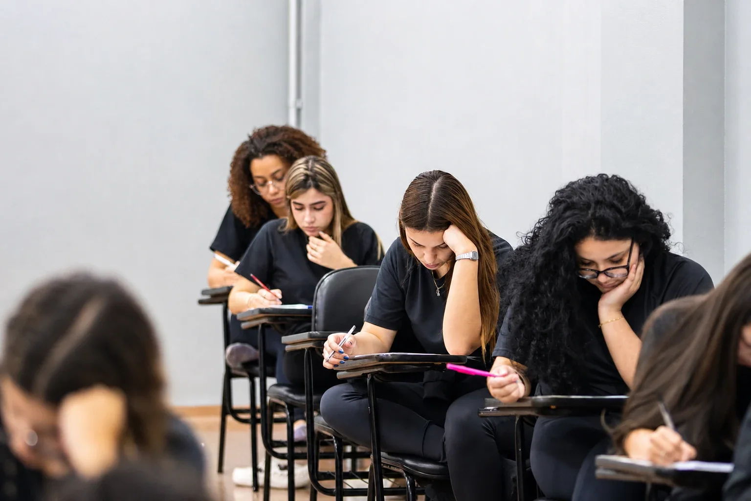 Fileira de alunos do Ensino Médio escrevendo nas carteiras