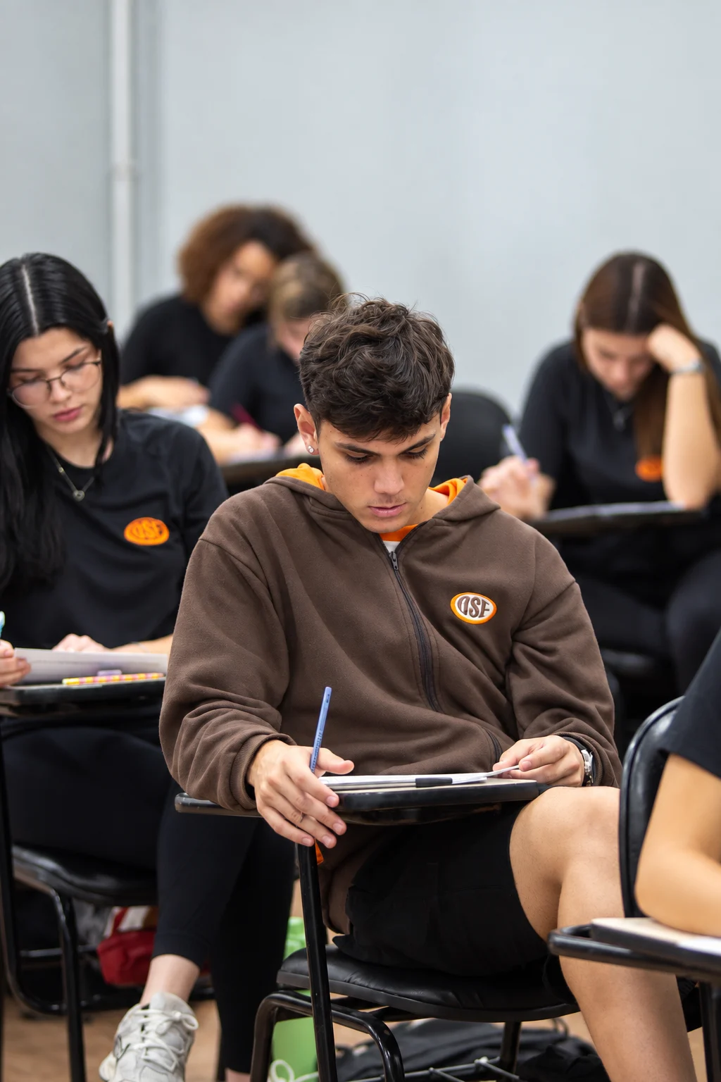 Aluno do Ensino Médio de moletom do uniforme resolve questões na carteira